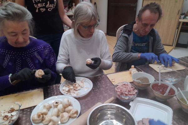 Mieszkańcy kroją produkty na pizze.