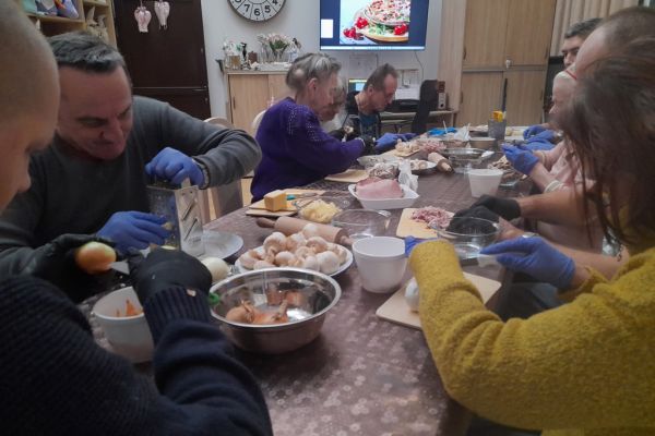 Mieszkańcy kroją produkty na pizze.