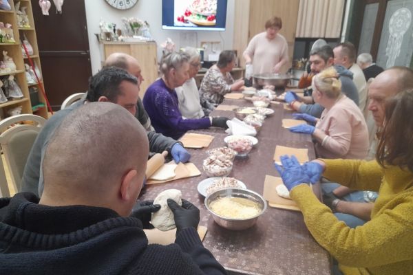 Mieszkańcy kroją produkty na pizze.