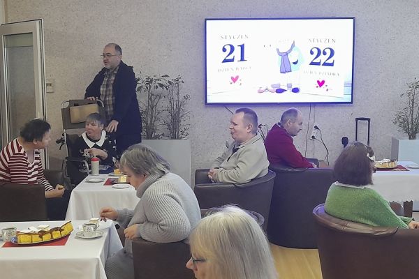 Mieszkańcy siedzą przy stolikach przy poczęstunku.