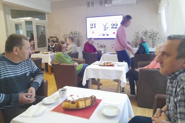 Mieszkańcy siedzą przy stolikach przy poczęstunku.