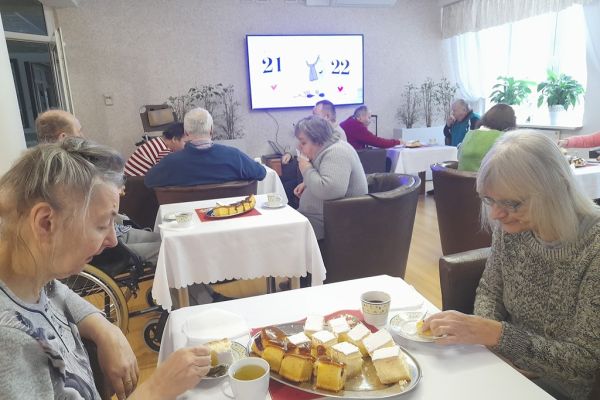 Mieszkańcy siedzą przy stolikach przy poczęstunku.