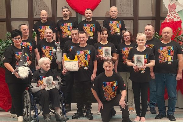 Grupowe zdjęcie mieszkańców w koszulkach WOŚP z gadżetami które przekażą na licytacje WOŚP.