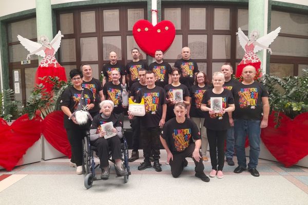 Grupowe zdjęcie mieszkańców w koszulkach WOŚP z gadżetami które przekażą na licytacje WOŚP.