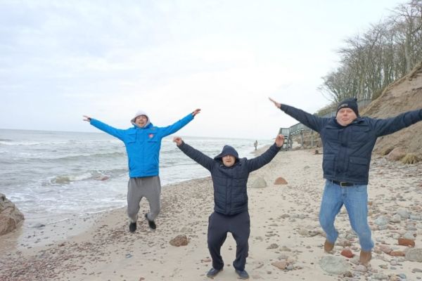 Trzech mieszkańców skacze z radości do góry nad morzem.