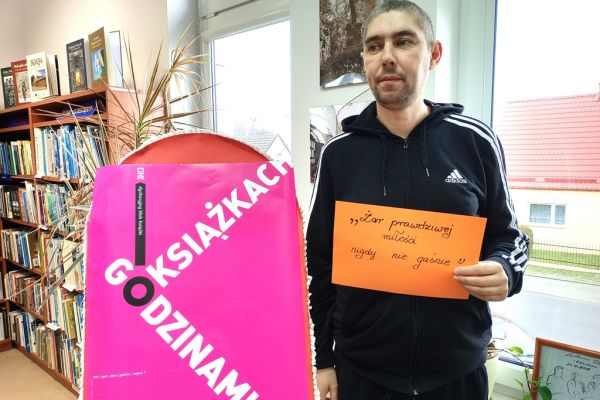 Mieszkaniec prezentuje cytat - przysłowie  na kartce a4 trzymanej przed sobą.