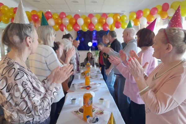 Mieszkańcy śpiewaja toast jubilatce na stojąco.