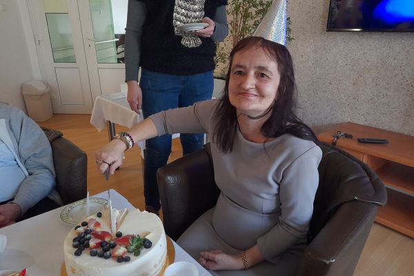 Jubilatka kroi tort siedząc przy stoliku.