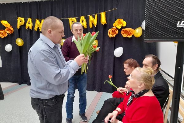 Dwoje Mieszkańców rozdaje tulipany kobietom.