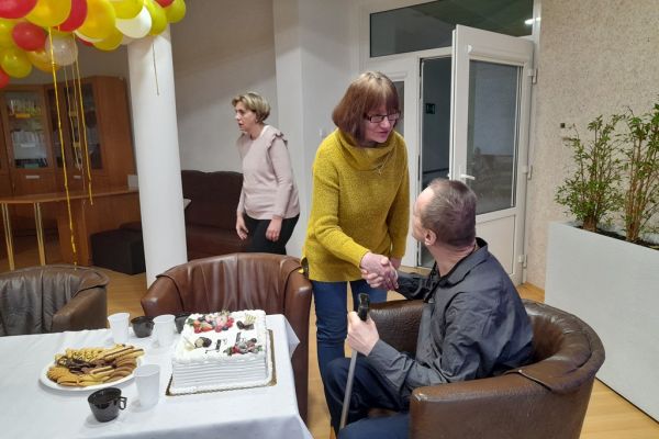 Mieszkanka składa życzenia siedzącemu solenizantowi.