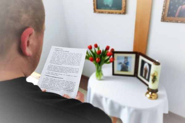 Mieszkaniec w małej kapliczce modli sie do obrazków świętych.