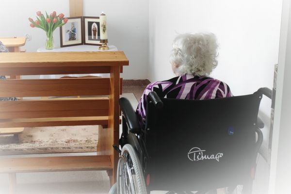 Mieszkanka w małej kapliczce modli sie do obrazków świętych.