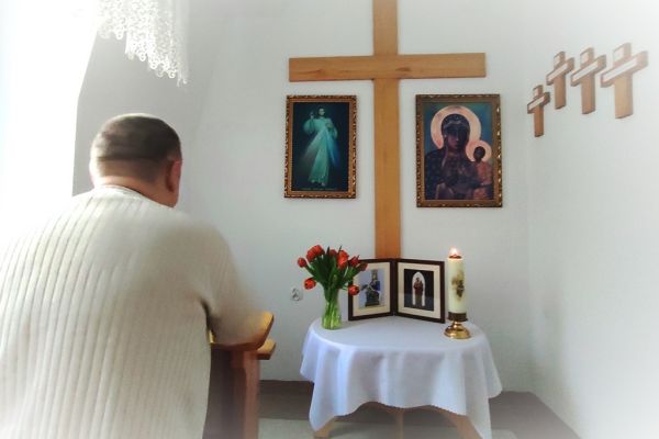 Mieszkaniec w małej kapliczce modli sie do obrazków świętych.