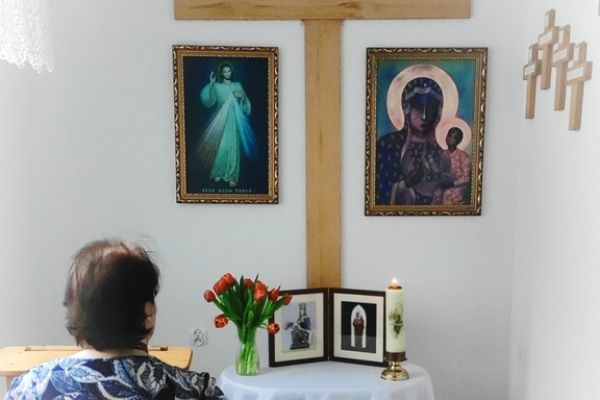 Mieszkanka w małej kapliczce modli sie do obrazków świętych.