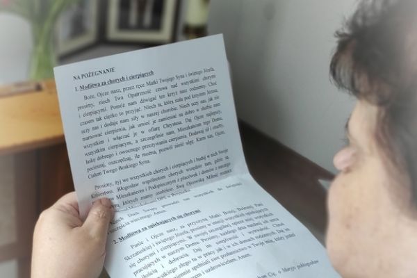 Mieszkanka w małej kapliczce modli sie do obrazków świętych.