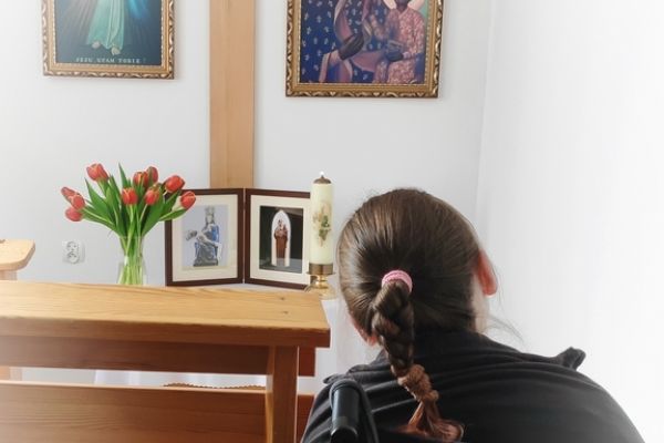 Mieszkanka w małej kapliczce modli sie do obrazków świętych.