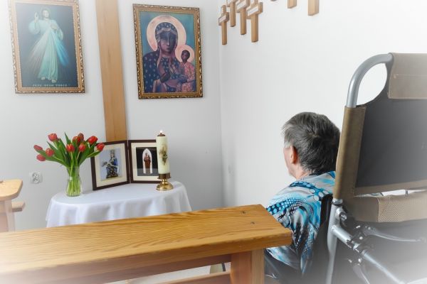 Mieszkanka w małej kapliczce modli sie do obrazków świętych.