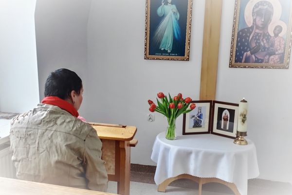 Mieszkanka w małej kapliczce modli sie do obrazków świętych.