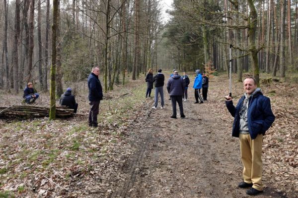 Mieszkańcy siedzą na pniach i stoją w lesie.