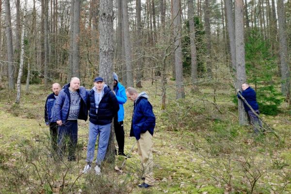 Mieszkańcy stoją w lesie przy drzewach..