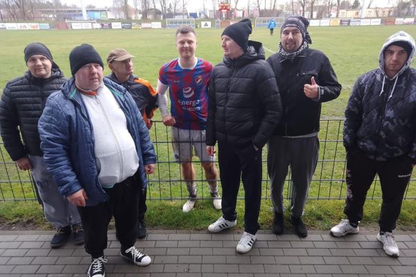 Mieszkańcy stoją przy boisku na meczu piłki nożnej.