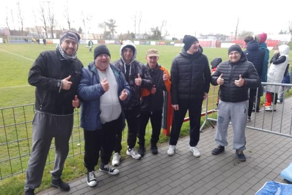 Mieszkańcy stoją przy boisku na meczu piłki nożnej.