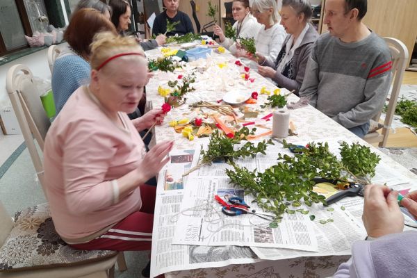Mieszkańcy wspólnie przy długim stole wykonują palemki.
