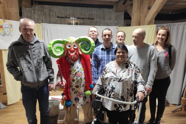 Grupowe zdjęcie mieszkańców z osobą występująca w przebraniu w sztuce.