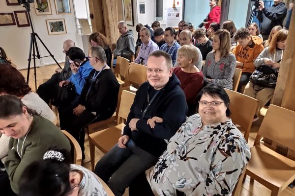 Mieszkańcy wraz z innymi uczestnikami oglądają spektakl.