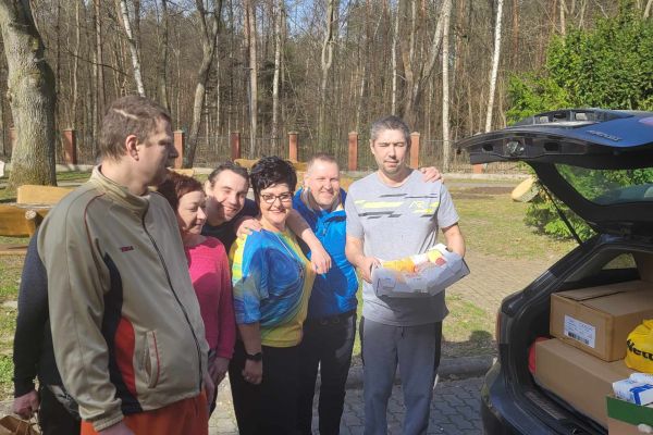 Mieszkańcy odebierają dary z samochodu. Grupowe zdjęcie przy aucie.