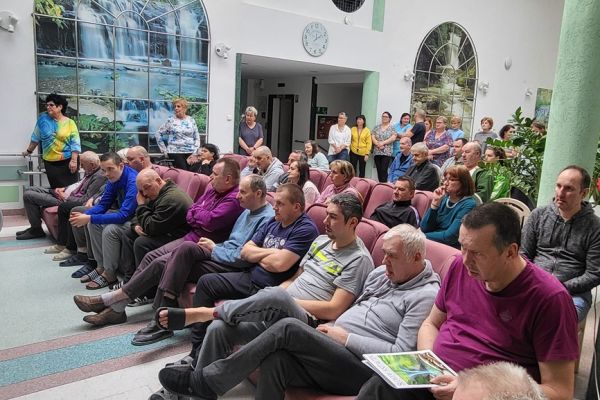 Mieszkańcy siedzą w rzędach foteli i krzeseł ustawionych na holu i oglądają film z projektora. 