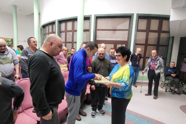 Pani Dyrektor rozdaje jajko  Mieszkańcom zgromadzonym na holu domu.