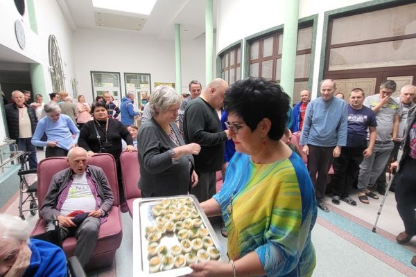 Pani Dyrektor rozdaje jajko  Mieszkańcom zgromadzonym na holu domu.