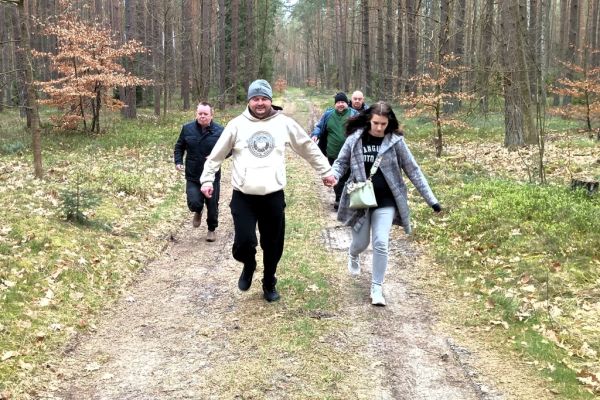 Mieszkańcy biegną ścieżką leśną.