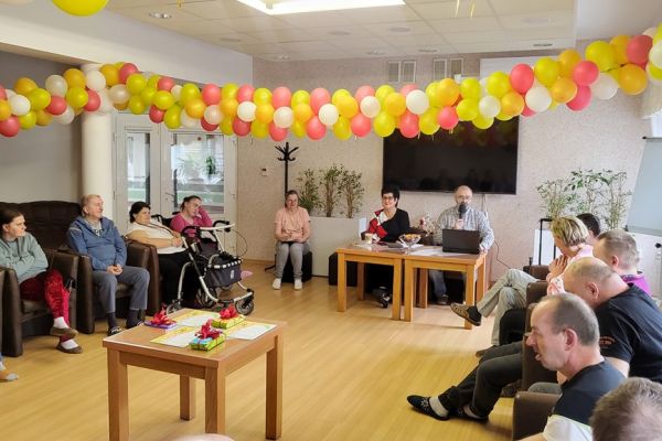 Uczestnicy quizu siedzą w fotelach a po środku przy stolikach siedzą prowadzący quiz.