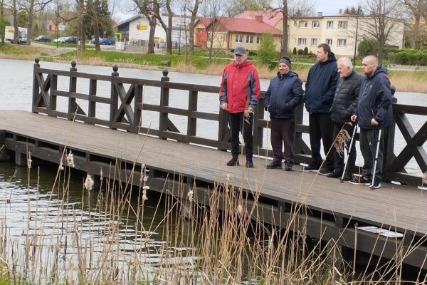 Pięcioro mieszkańców nad jeziorkiem na pomoście.