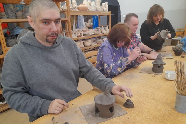 Kilkoro mieszkańców lepi z gliny domek.