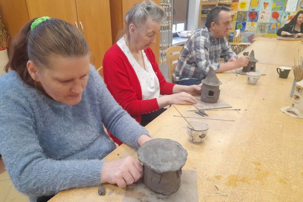 Kilkoro mieszkańców lepi z gliny domek.