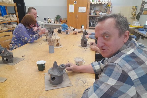 Kilkoro mieszkańców lepi z gliny domek.