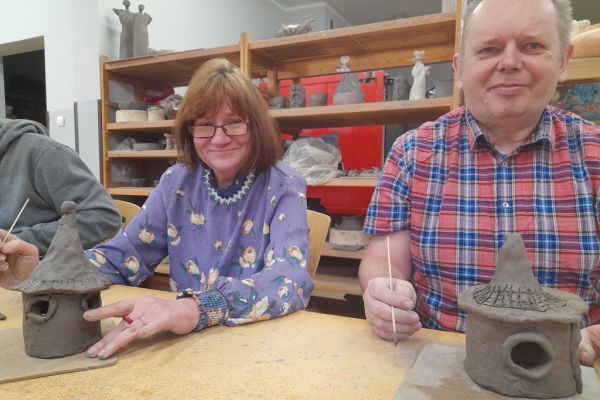 Pan i pani  lepią z gliny domek.