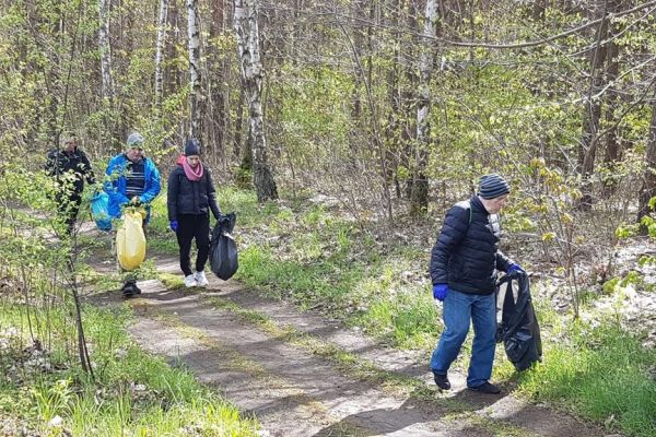 Kilkoro mieszkańców sprząta miejscowość , zdjęcie w lesie..