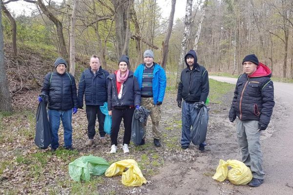 Kilkoro mieszkańców sprząta miejscowość, zdjęcie grupowe z napełnionymi workami.