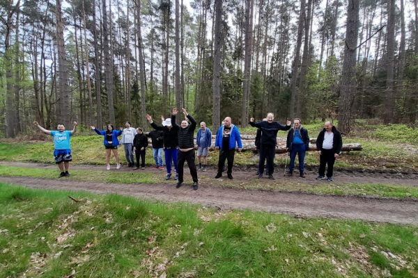 Mieszkańcy wykonują drobne ćwiczenia gimnastyczne w środku lasu.