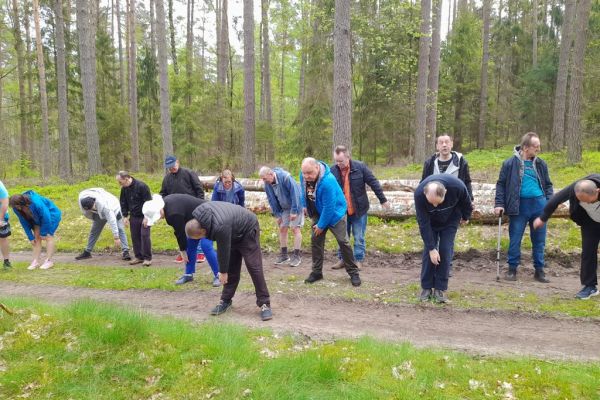 Mieszkańcy wykonują drobne ćwiczenia gimnastyczne w środku lasu.