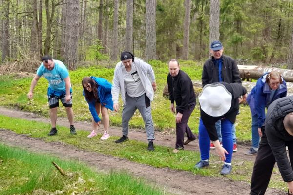 Mieszkańcy wykonują drobne ćwiczenia gimnastyczne w środku lasu.