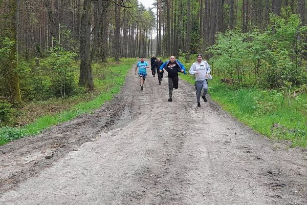 Mieszkańcy biegną przez las.