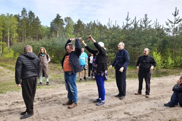 Mieszkańcy wykonują drobne ćwiczenia gimnastyczne w środku lasu.