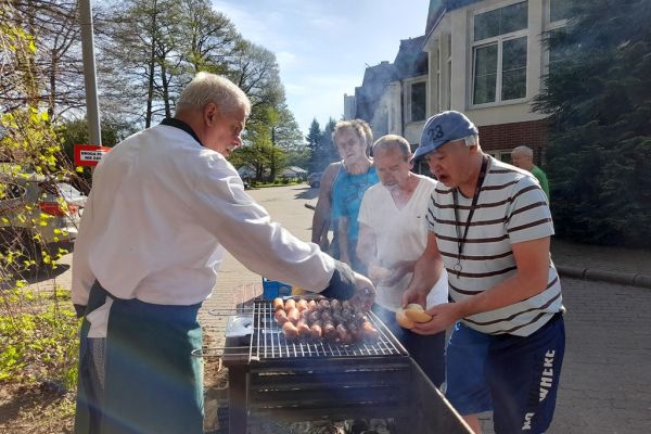 Mieszkańcy częstują się grillem.