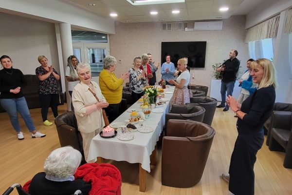 Mieszkańcy na stojąco śpiewają sto lat jubilatce.