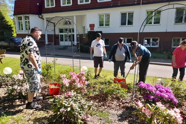 Mieszkańcy sprzątają kląb z kwiatami przy Domu.